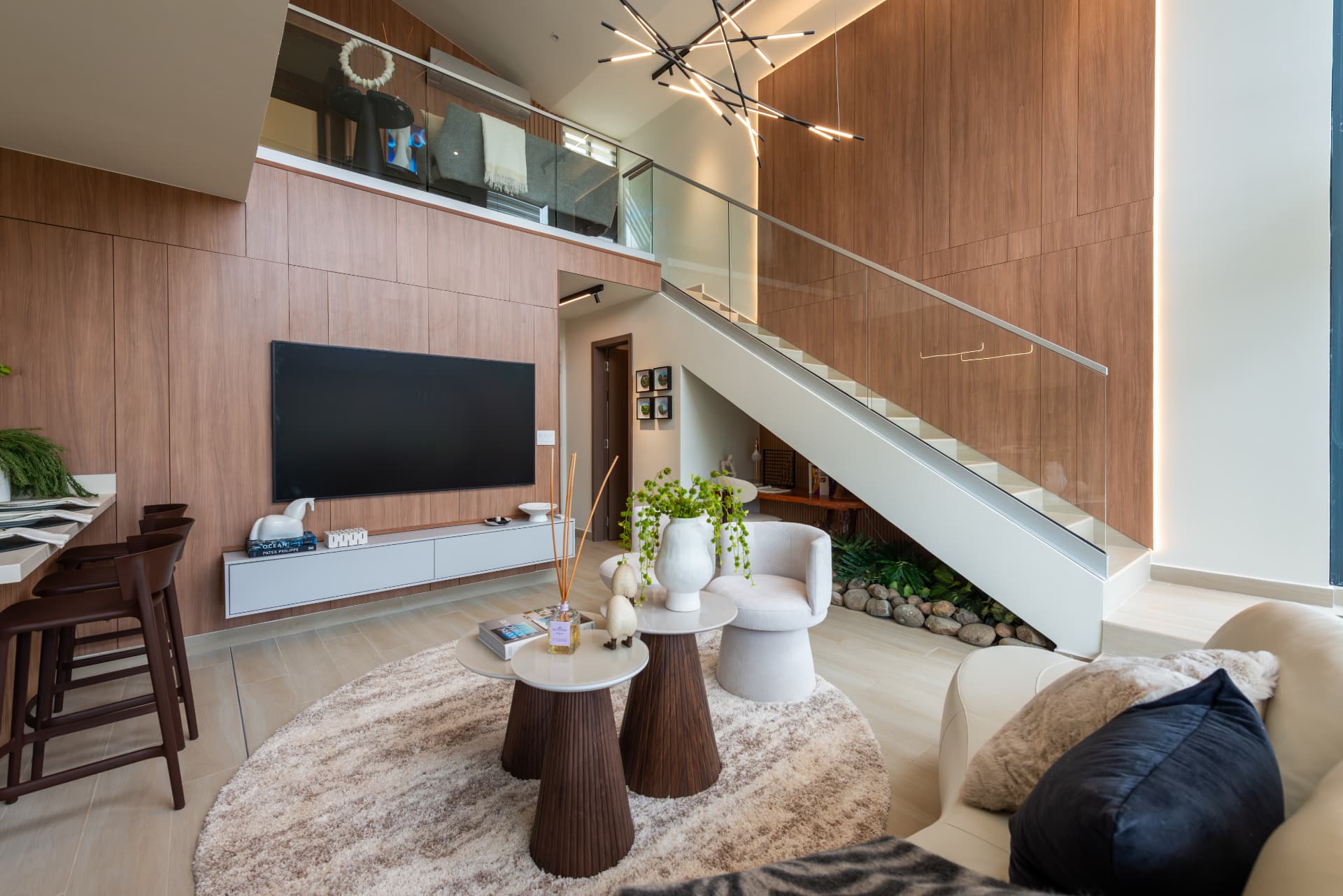 Interior de doble altura con escalera, madera y sala de estar en Casa Aria